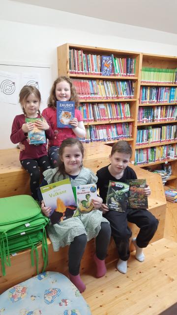 Kinder sitzen auf Stiege mit Büchern in der Hand